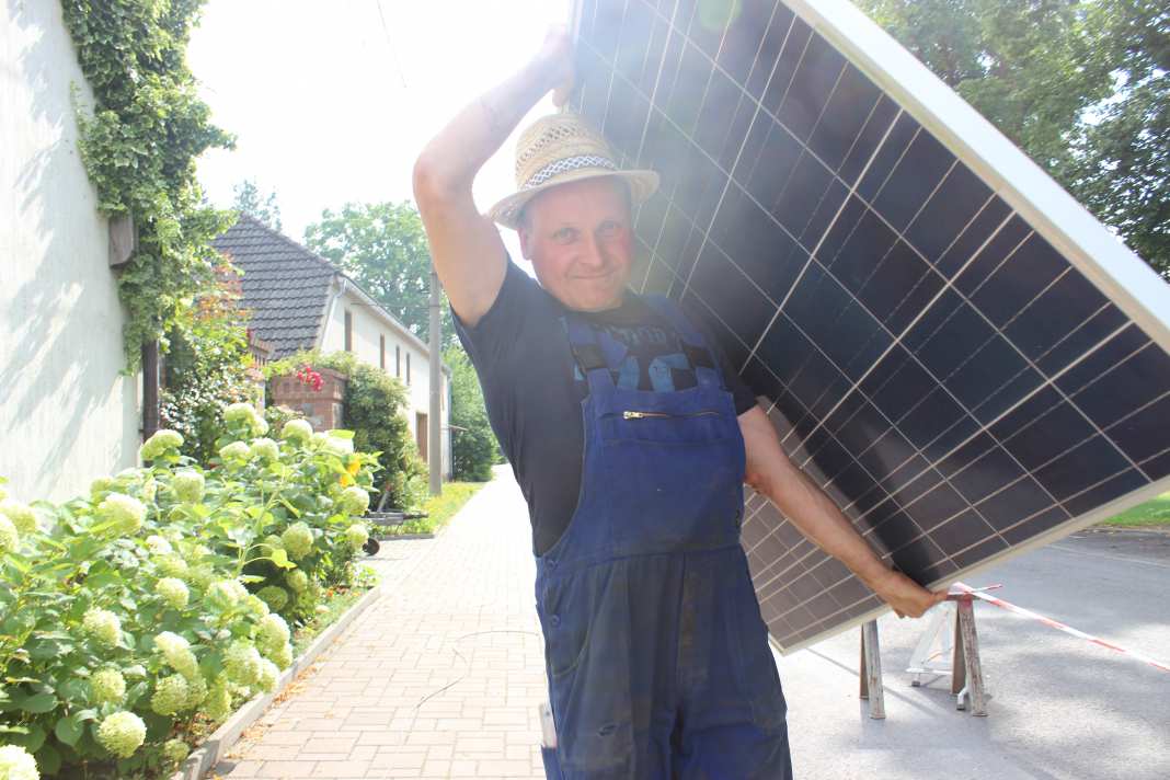 Frank Lehmann beim Tragen eines Solarmoduls.