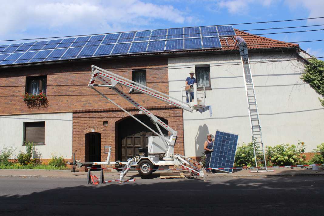 Blick auf das Haus während der Montage der Solarmodule mithilfe einer Hebebühne.