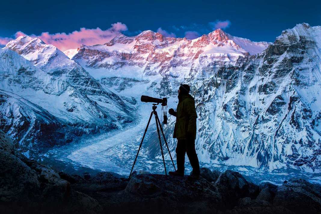 Ein Naturfotograf auf einem verschneiten Bergipfel.