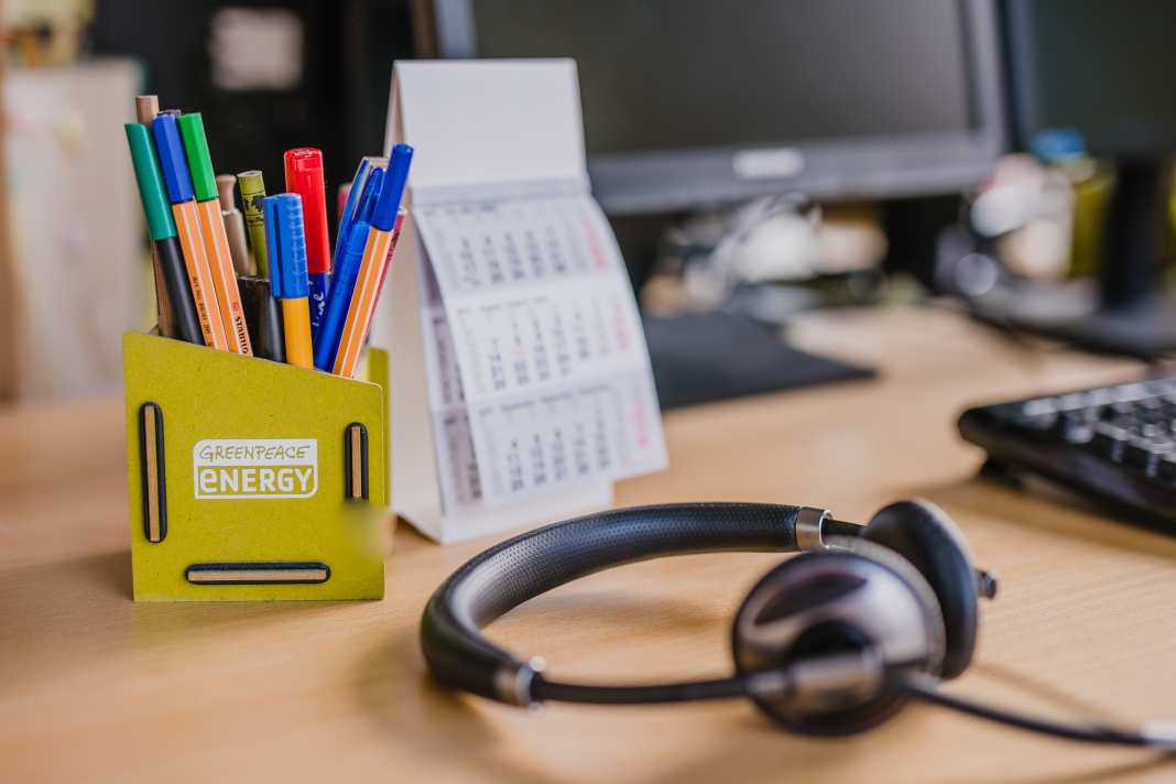 Schreibtisch mit Headset und Stiftebox mit Green Planet Energy Logo