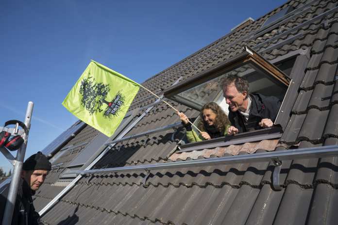 Antje Grothus und Norbert Heinen schauen aus ihrem Dachfenster und bejubeln die neue Solaranlage auf ihrem Dach.