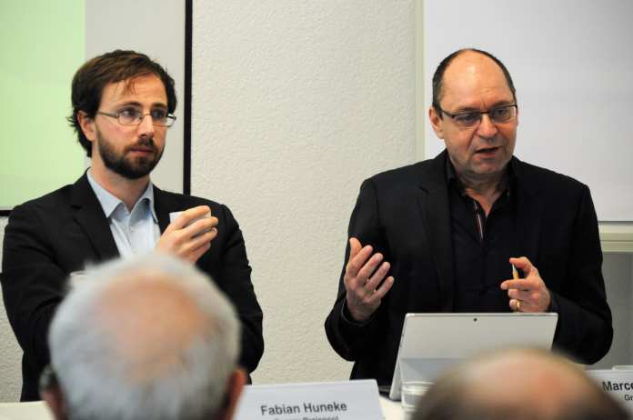 Pressekonferenz: Fabian Huneke neben gestikulierendem Mann
