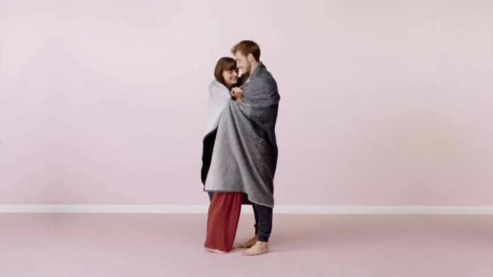 Ein Mann und eine Frau umarmen sich mit einer Decke.