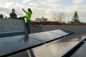 Green Planet Energy Mitarbeitende auf einem Dach mit Solaranlage im Gespräch