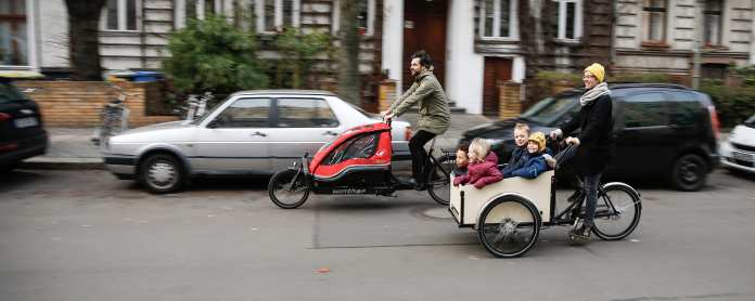 Ein Mann und eine Frau fahren nebeneinander durch die Stadt auf Cargobike- Lastenrädern.