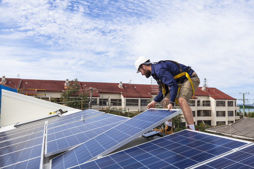 Fachhandwerker montiert Solarpaneele auf einem Dach.