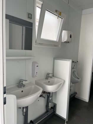 Ein Badezimmer mit zwei Waschbecken und einem Pissoir.