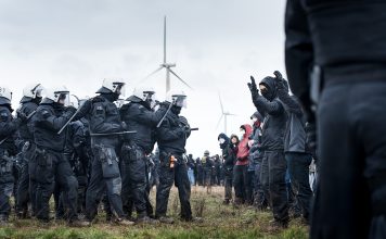 Polizeikette steht vor einer Gruppe Demonstrierender.