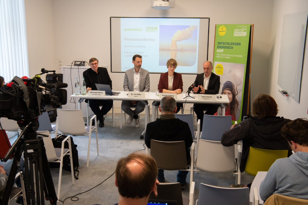Pressekonferenz: Green Planet Energy Mitarbeiter:innen sitzen vor einem Publikum. Im Hintergrund ist eine Power Point Präsentation mit abgebildetem Atomkraftwerk zu sehen.