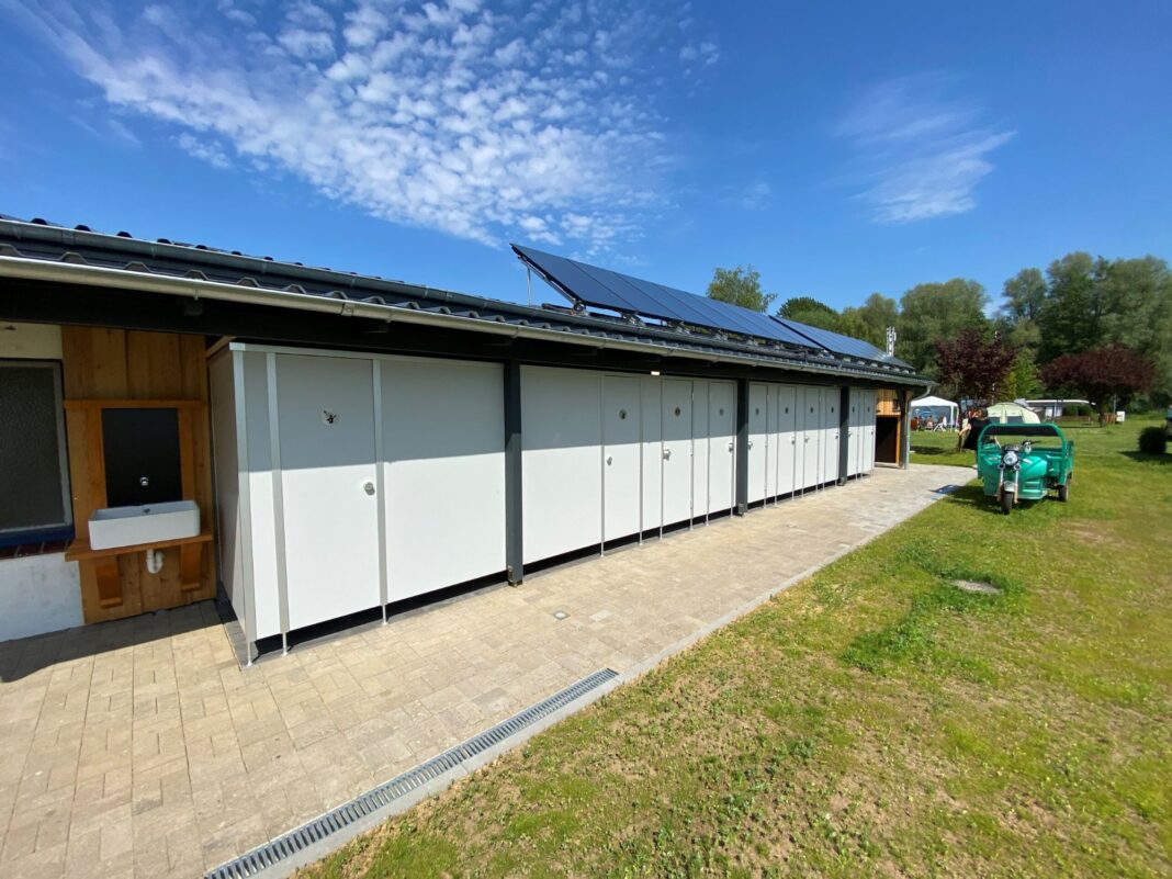 Sanitärhäuschen auf einem Campingplatz. Auf dem Dach sind Solarmodule angebracht.