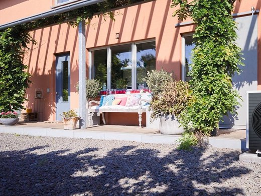 Eine installierte Wärmepumpe liefert einem mit Pflanzen umgebenen Bestandsgebäude Wärmepumpenstrom.