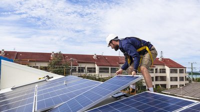Handwerker montiert Photovoltaikanlage auf Hausdach