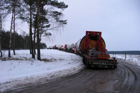 Eine Lkw-Karawane fährt auf einer verschneiten Straße.