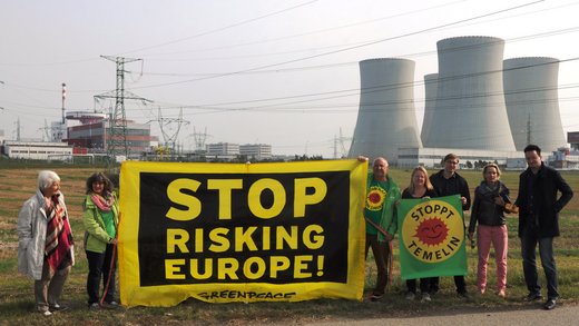 Die Demonstranten halten ein Banner mit der Aufschrift "Stop Risking Europe" in englischer Sprache hoch. Im Hintergrund ein Atomkraftwerk.