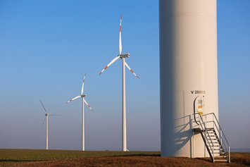 Windpark Wundersleben bei blauem Himmel: Im Voddrgrund ein angeschnittenes Windrad, im Hintergrund 3 weitere Windräder.