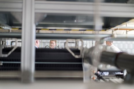 Hinter einem Elektrolyseur unterhalten sich zwei Männer