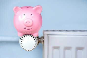Rosa Sparschwein sitzt auf Heizungsthermostat.