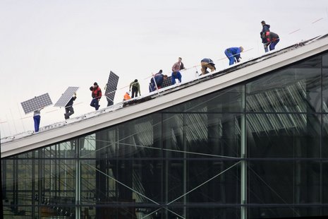 Leute verlegen Photovoltaikmodule auf einem Dach
