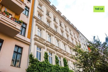 Ausschnitt eines Altbau-Hauses. Links befindet sich eine gelbe Sprechblase mit dem Text "Blogserie Teil 12".