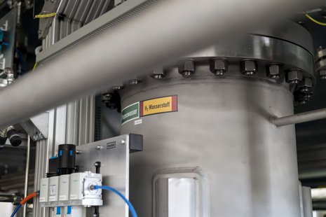 Teil eines Elektrolyseurs aus der Nahansicht mit Aufschrift "H2 Wasserstoff"