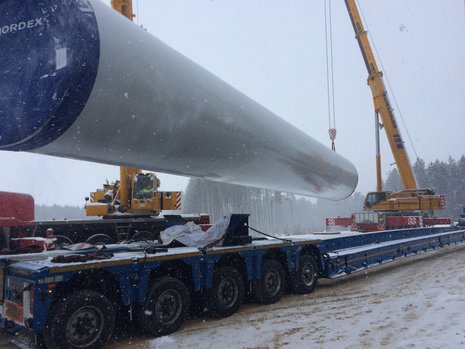 Stahlrohrturmsegment wird von Kran bei Schneefall hochgezogen