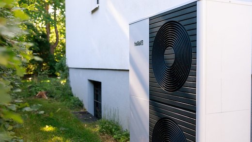 Wärmepumpe steht direkt an einem Bestands-Gebäude im Garten.
