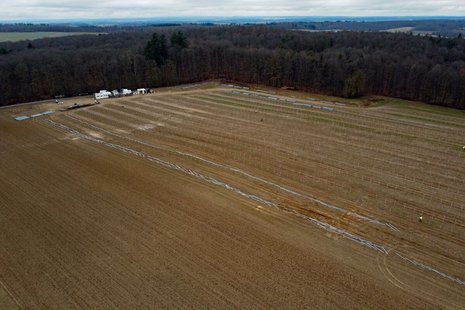 Offenes Stoppelfeld am Rande eines Waldes, das bebaut wird.