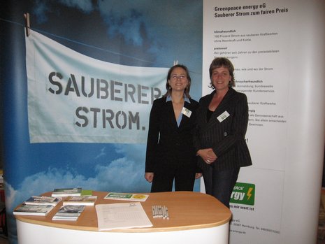 Greenpeace Energy Stand mit zwei Mitarbeiterinnen vor einem Plakat mit dem Aufdruck: "Sauberer Strom".