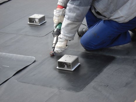 Die Hand einer Person beim Abdichten eines Daches