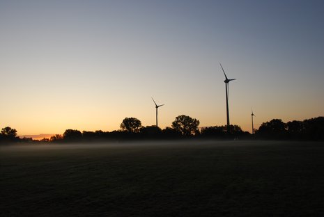 Drei Windkraftanlagen bei Sonnenuntergang