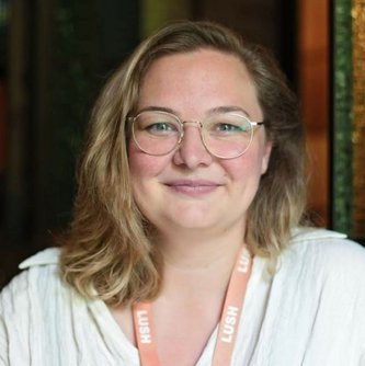 Eine Frau mit Brille und schulterlangen Haaren lächelt in die Kamera.