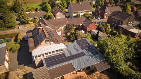 Luftaufnahme von einem Einfamilienhaus mit Solaranlage auf dem Dach.