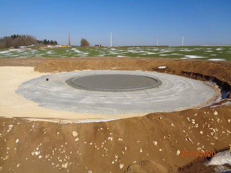 Eine Vertiefung in der Erde. Die Erde wurde kreisförmig an den Rand geschoben. In der Mitte ist ein kreisförmiges Fundament entstanden.