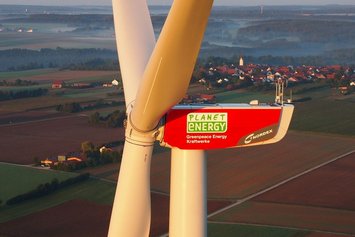 Windenergieanlage in Nahaufnahme mit roten Maschinenhaus und Planet energy Logo