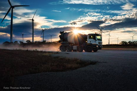 Ein Lastwagen fährt auf einer Straße mit Windrädern im Hintergrund.