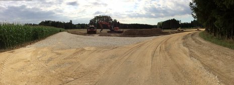 Geebneter Weg zu Baugrube, an der ein Bagger zugange ist