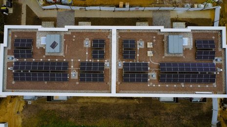 Flachdach mit in mehreren Reihen angeordneten Photovoltaikmodulen und Wärmepumpen.