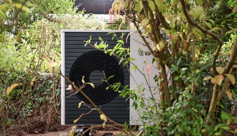 Neu installierte Wärmepumpe im Garten zwischen Gebüsch und Bäumen.