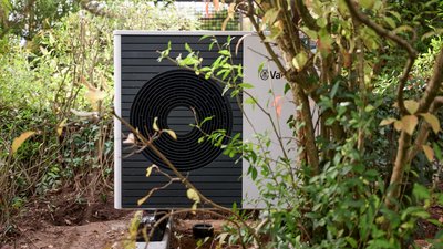 Neu installierte Wärmepumpe im Garten zwischen Gebüsch und Bäumen.