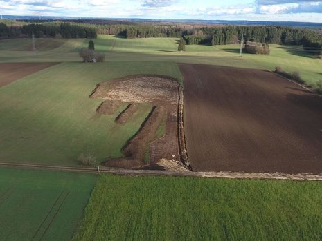 Eine Landschaft mit Feldern. Eines der Felder wurde zum Teil umgegraben.