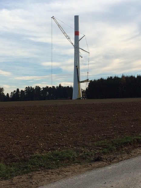 Vor einem im Bau befindlichen Windkraftturm steht ein Kran
