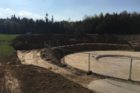 Rundes Erdloch mit umlaufendem Zaun.