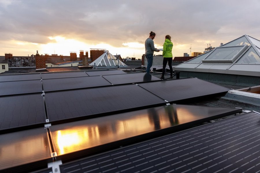 Zwei Personen hinter einem Solarkraftwerk auf einem Dach unterhalten sich.