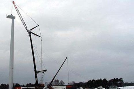 Ein Kran montiert die Turbine an einer Windkraftanlage, die auf einem verschneiten Feld errichtet wurde.