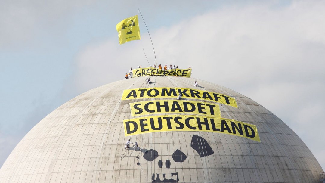 Auf der grauen Kuppel eines Atomkraftwerks stehen mehrere Menschen und halten ein Transparent mit "Greenpeace" hoch. Auf weiteren Transparenten steht "Atomkraft schadet Deutschland".