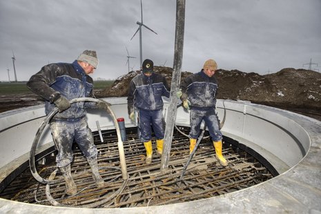 Gießen von Beton in den Fundamentkorb durch drei Arbeiter.