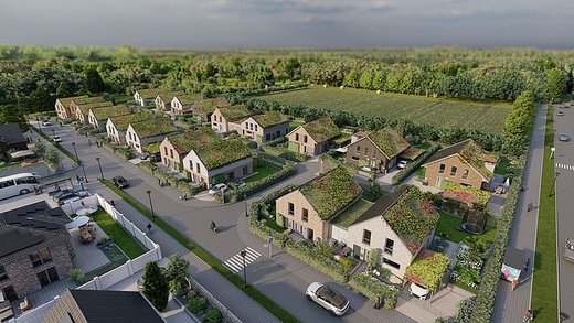 Vogel-Perspektive einer Neubau-Wohnsiedlung. Die Häuser haben begrünte Dächer und sind umgeben von Feldern und Straßen.