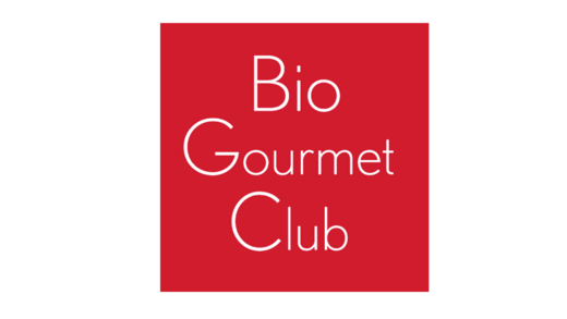 Ein rotes Quadrat zeigt den Text "Bio Gourmet Club" in weißer Schrift. Der Hintergrund ist einfarbig rot, während der Schriftstil elegant und modern erscheint.