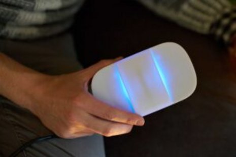 Eine Hand, die ein weißes Gerät mit Plastikgehäuse und zwei Leuchtstreifen hält