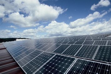 Photovoltaikanlage auf einem Flachdach bei bewölktem Himmel.